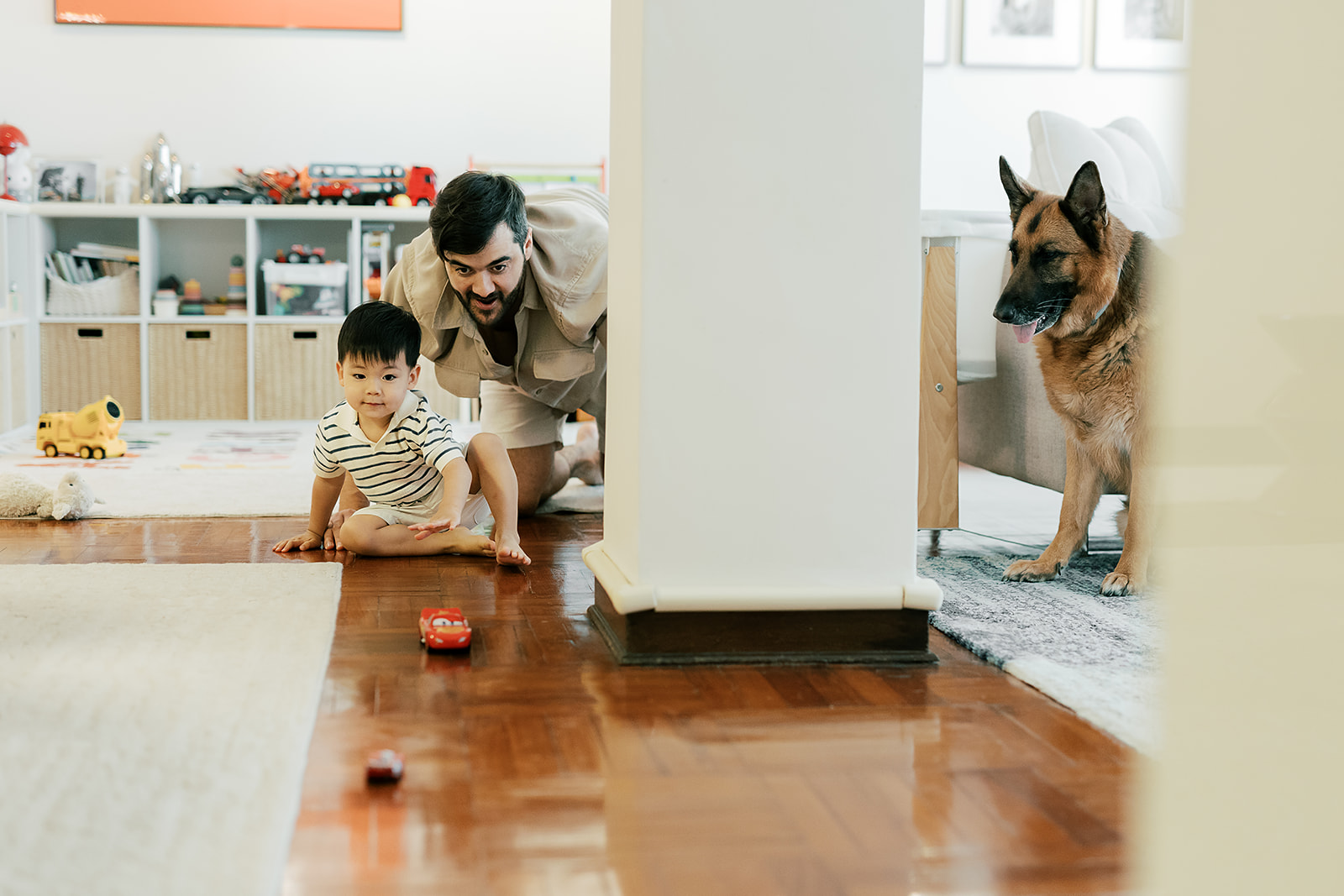 Dad and son playing on the living room floor, toys scattered around.