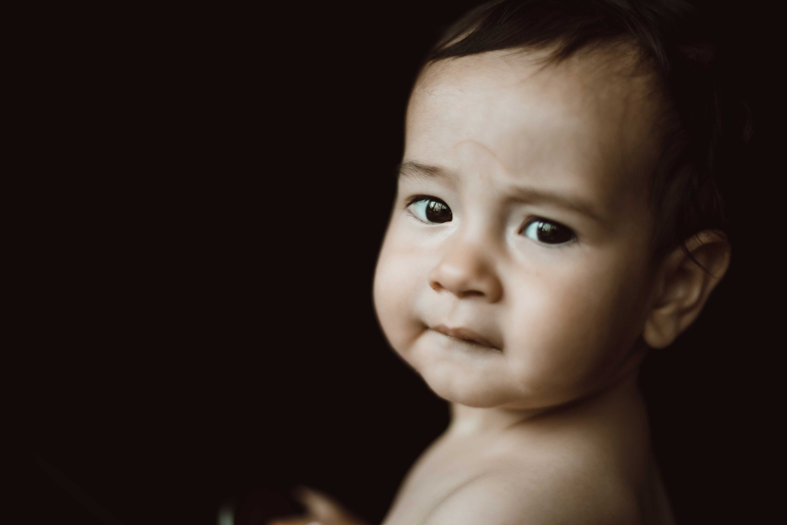 Baby boy looking at the camera in black background