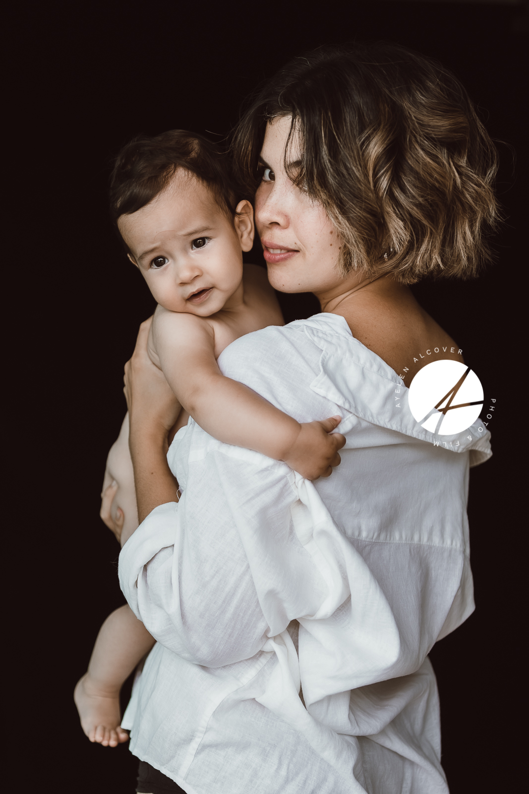 Mother carrying baby on her arms while both looking at the camera