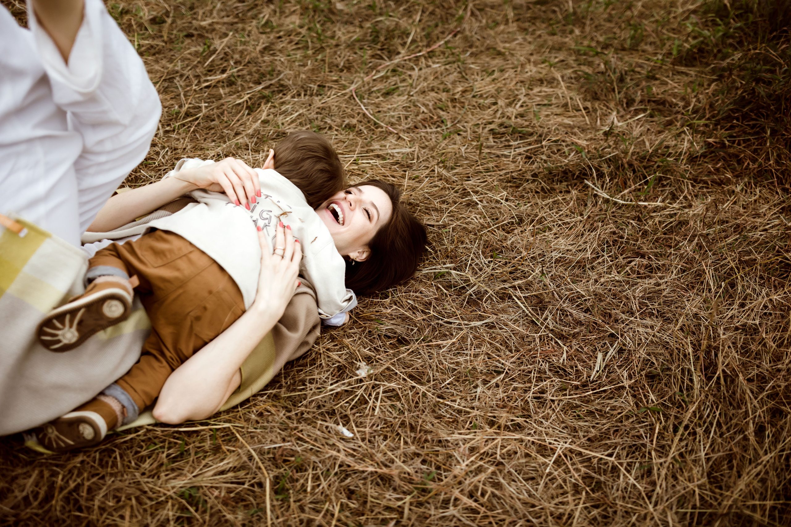 Baby boy hugging his mother while both laying on the ground in a candid moment